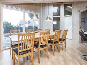 A dining area with wooden tables and chairs, large windows, and a view of the outside. - 5 Star Holiday Home in Harboore (Harboore)