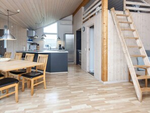 A modern kitchen with a central island, wooden dining table, and chairs. - 5 Star Holiday Home in Harboore (Harboore)
