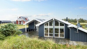 Une maison moderne dotée d’une grande baie vitrée et d’un toit en pente.