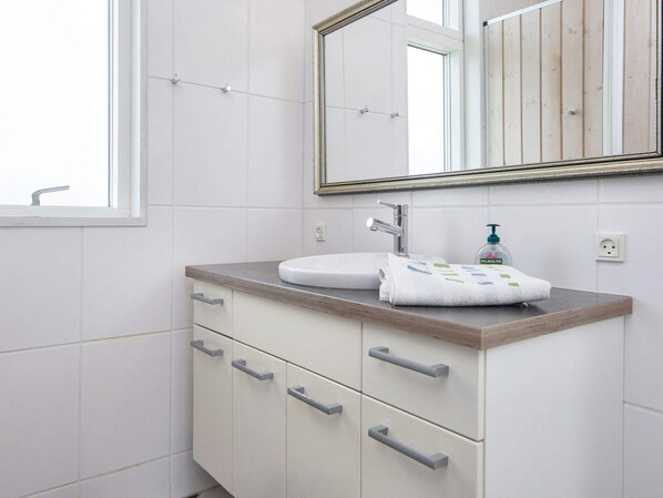 A bathroom with a white sink, a mirror, and a towel on the counter.