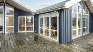 Une maison moderne dotée de grandes fenêtres en verre et d’une terrasse en bois.