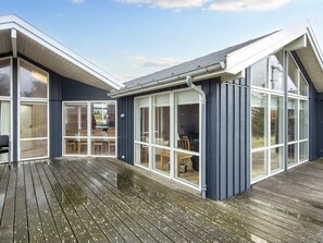 Una casa moderna con ampie vetrate e un terrazzo in legno.