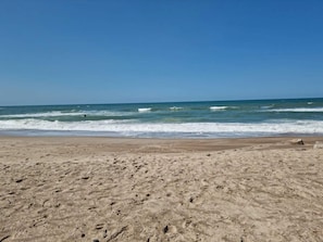 Platja sorrenca amb ones, cel serè i sense estructures visibles.