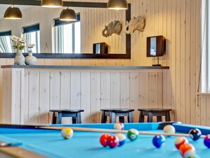 A pool table with balls, wooden walls, and two tables with chairs. - 5 Star Holiday Home in Bogense (Bogense)