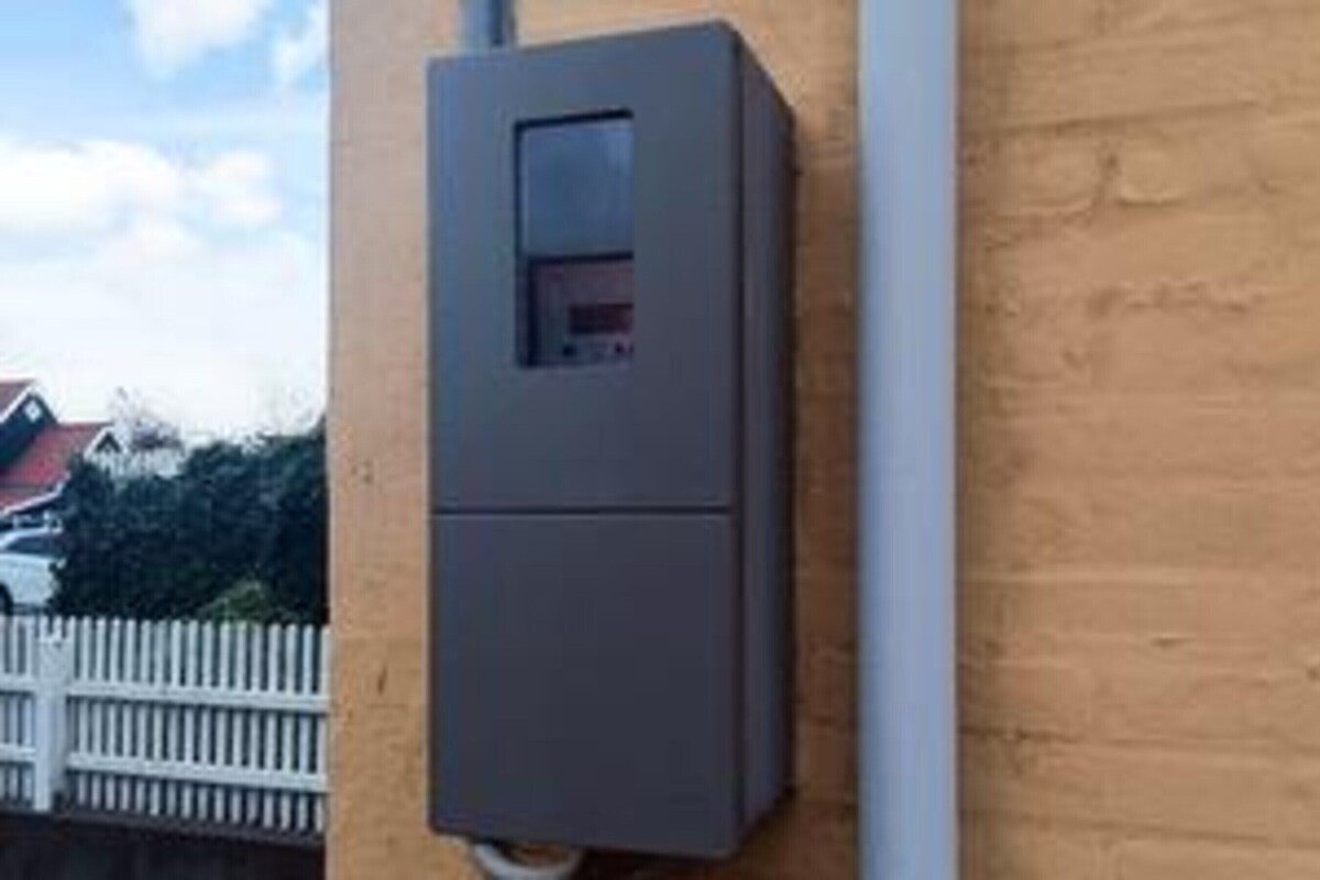 Une boîte électrique grise fixée à un mur.