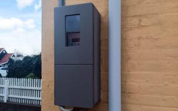 Une boîte électrique grise fixée à un mur.