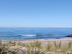 A beach with clear blue water and a sandy shore.