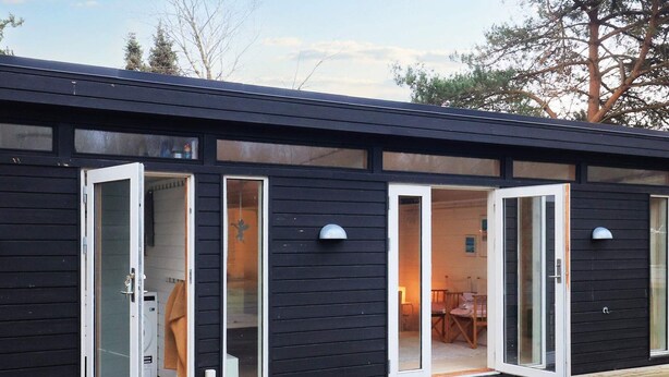 Un bâtiment moderne doté de grandes portes vitrées qui donnent sur une pièce comprenant un lit et un bureau.