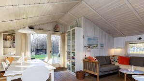 Un salon chaleureux avec un coin repas, un plancher en bois et une vue à travers une porte vitrée.