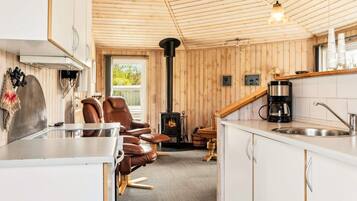 A cozy cabin interior with a kitchen, dining area, and a fireplace.