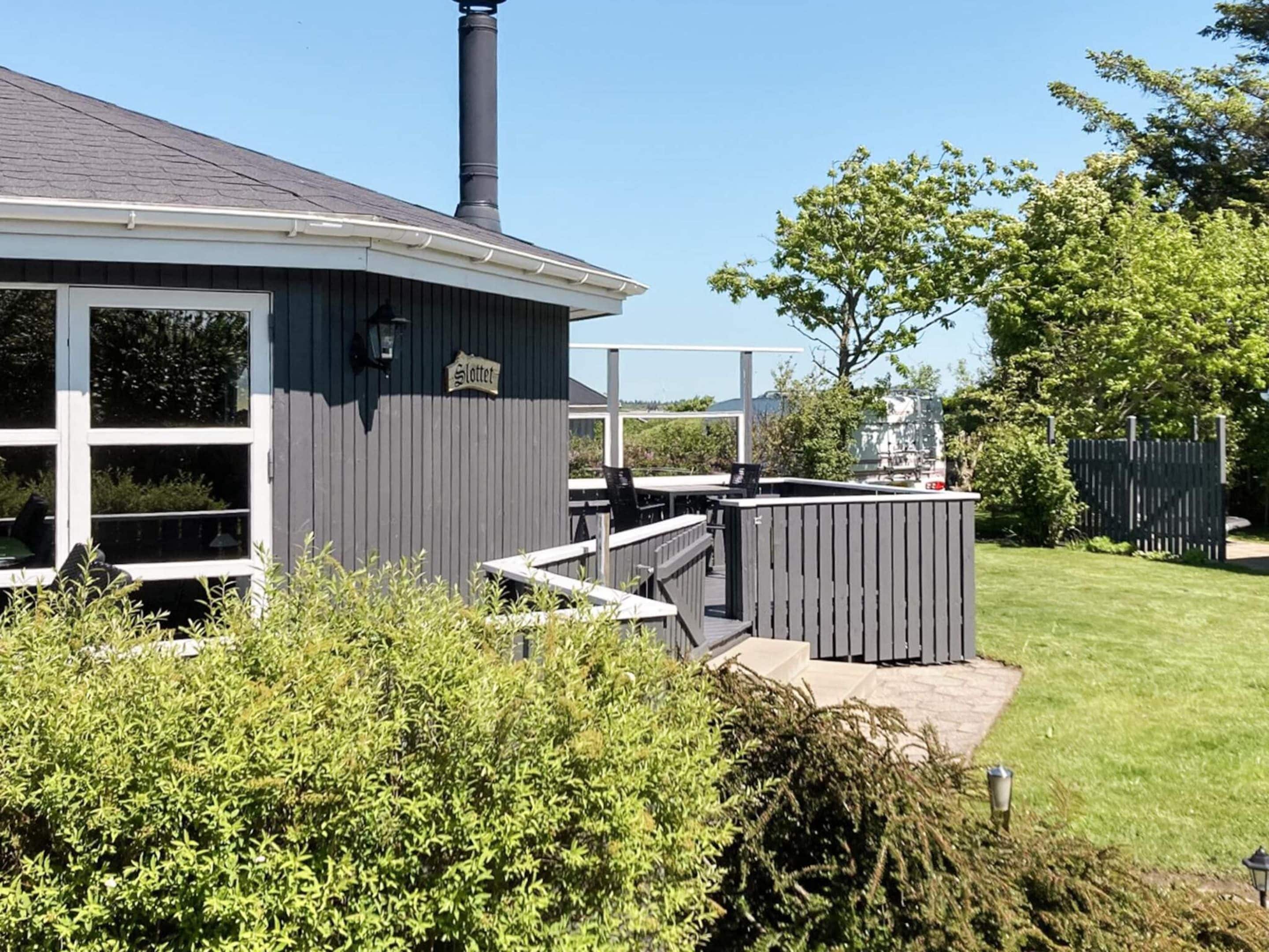 A house with a covered outdoor area, a chimney, and a sign that reads 'Slottet.'