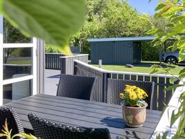Una terraza con mobiliario exterior, una planta en maceta y un cobertizo al fondo.