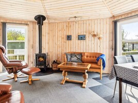Una habitación acogedora con paredes de madera, un sofá, una silla, una mesa y una chimenea.