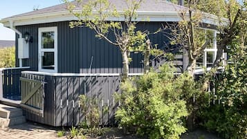 A residential house with a dark exterior, a front deck, and a small garden area.