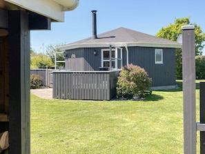 A single-story house with a fenced backyard, a chimney, and a small deck. - 4 Person Holiday Home in Vinderup (Vinderup)