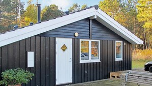 A cabin with a white door, a small window, and a wooden deck. - Adorable Holiday Home in Lolland near Sea (Rodby)