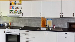 A modern kitchen with white cabinets, a built-in oven, a dishwasher, and a black countertop. - 7 Person Holiday Home in Averoy (Averoy)