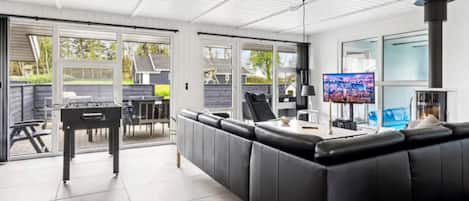 A modern living area with a black leather sofa, a television, and a fireplace.