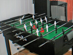 Una mesa de futbolín con superficie de juego verde y bordes negros.