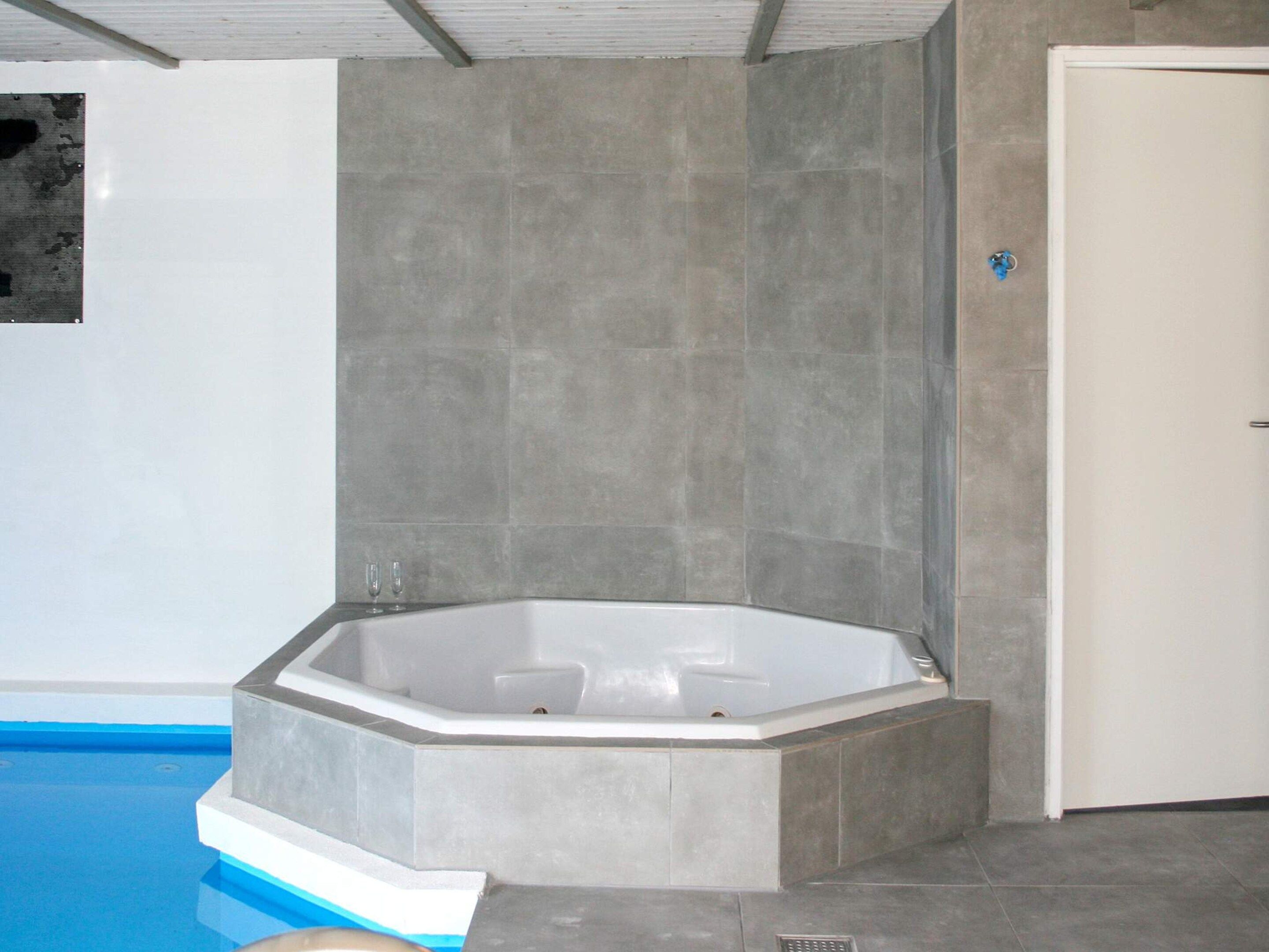 Un baño moderno con una bañera independiente, paredes con azulejos y zona de ducha.