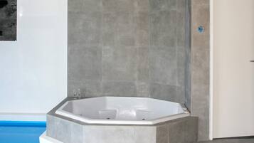 Un baño moderno con una bañera independiente, paredes con azulejos y zona de ducha.