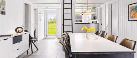Une cuisine moderne avec une grande table à manger, des chaises noires et une vue sur l’extérieur.