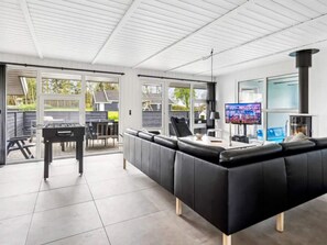 Una sala de estar moderna con un sofá de cuero negro, un televisor y una chimenea.