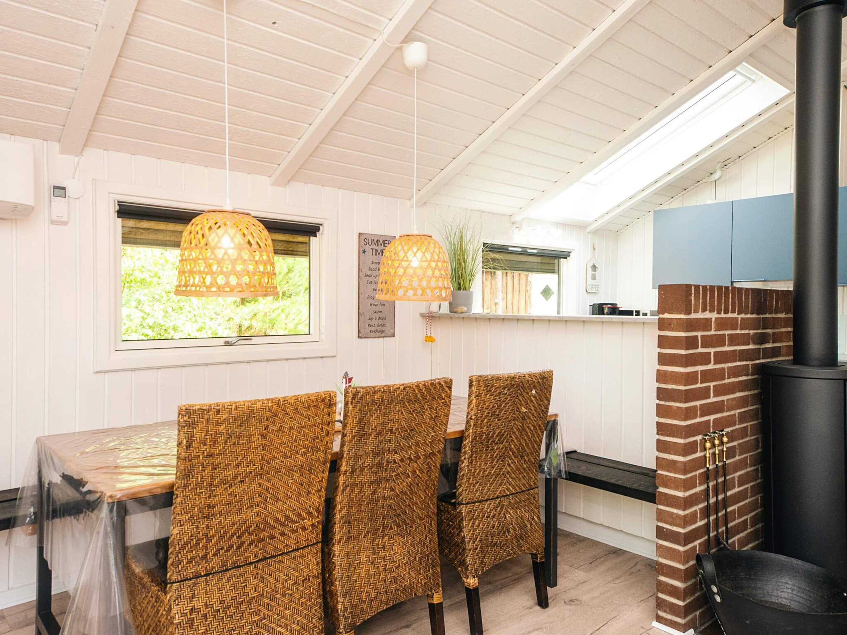 A dining area with wicker chairs, a table, and a hanging light fixture.