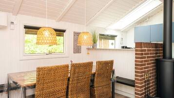 A dining area with wicker chairs, a table, and a hanging light fixture.