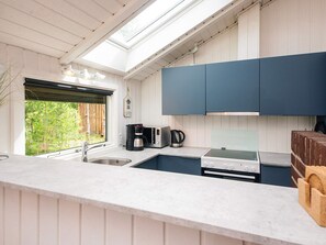 A modern kitchen with a skylight, a coffee machine, a toaster, and a stove.