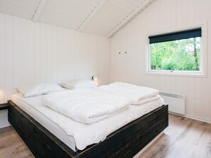Quarto com cama, janela e aquecedor fixado na parede.