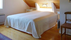 A bedroom with a sloped wooden ceiling, a bed with a white bedspread, a nightstand, a chair, and a window with curtains. - 5 Person Holiday Home in Nordingra-by Traum (Nordingra)