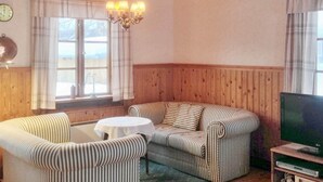 A cozy room with a striped sofa, a small round table, a television, and a window with curtains. - 5 Person Holiday Home in Nordingra-by Traum (Nordingra)