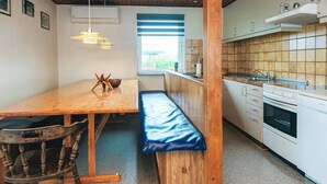 A compact kitchen with wooden cabinetry, a built-in oven, and a window with blinds. - 10 Person Holiday Home in Harboore (Harboore)