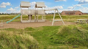 A playground with two wooden playhouses, a slide, and swings. - 10 Person Holiday Home in Harboore (Harboore)