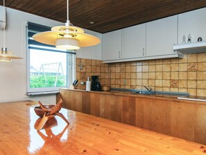 A modern kitchen with wooden cabinets, a stainless steel sink, and a large window. - 10 Person Holiday Home in Harboore (Harboore)