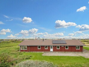 A red building with a flat roof, solar panels, and a clear sky.