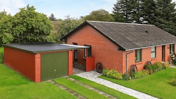 A red brick building with a green shed, surrounded by a well-maintained lawn and trees.