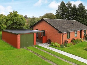 A red brick building with a green shed, surrounded by a well-maintained lawn and trees. - Cozy Holiday Home in Syddanmark near Sea (Aeroskobing)