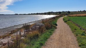 A coastal path with a view of the sea and distant houses. - Cozy Holiday Home in Syddanmark near Sea (Aeroskobing)