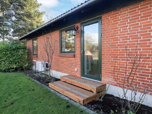 A brick building with a green door, a window, and a small wooden porch. - Cozy Holiday Home in Syddanmark near Sea (Aeroskobing)