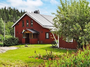 A red wooden house with a sloped roof, a porch, and a flag. - 6 Person Holiday Home in Bengtsfors (Bengtsfors)