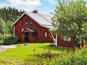 Ein rotes Holzhaus mit geneigtem Dach, einer Veranda und einer Flagge.