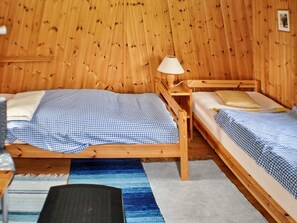 A wooden room with two beds, a lamp, and a small table.