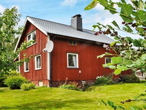 Een rode houten woning met schuin dak, schotelantenne en een verzorgd gazon.