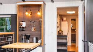 A modern kitchen with a wooden accent wall, coffee machine, and a view into the adjacent dining area. - Refined Holiday Home in Glesborg near Sea (Glesborg)