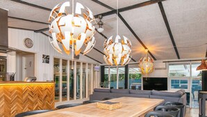 A modern dining area with a long wooden table, black chairs, and two large spherical pendant lights. - Refined Holiday Home in Glesborg near Sea (Glesborg)