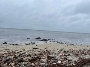 Een rotsachtig strand met kalm water en een bewolkte lucht.