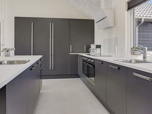 A modern kitchen with grey cabinets, stainless steel appliances, and a window with a view. - 5 Star Holiday Home in Stege (Stege)