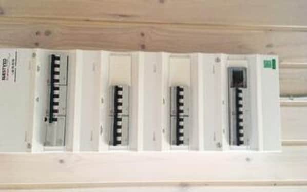 A white electrical panel with multiple switches and a green label.